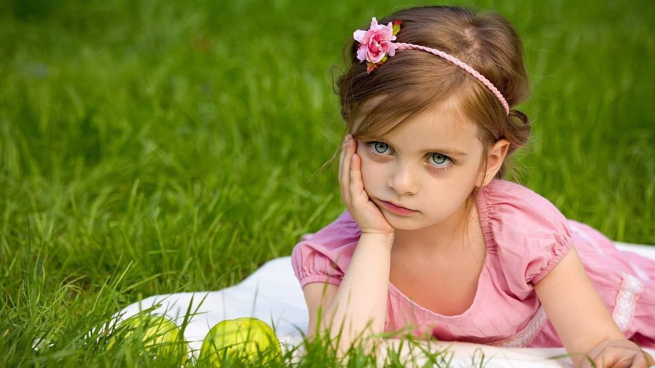 Fussy eater - Girl looking unimpressed lying in grass with chin on hand