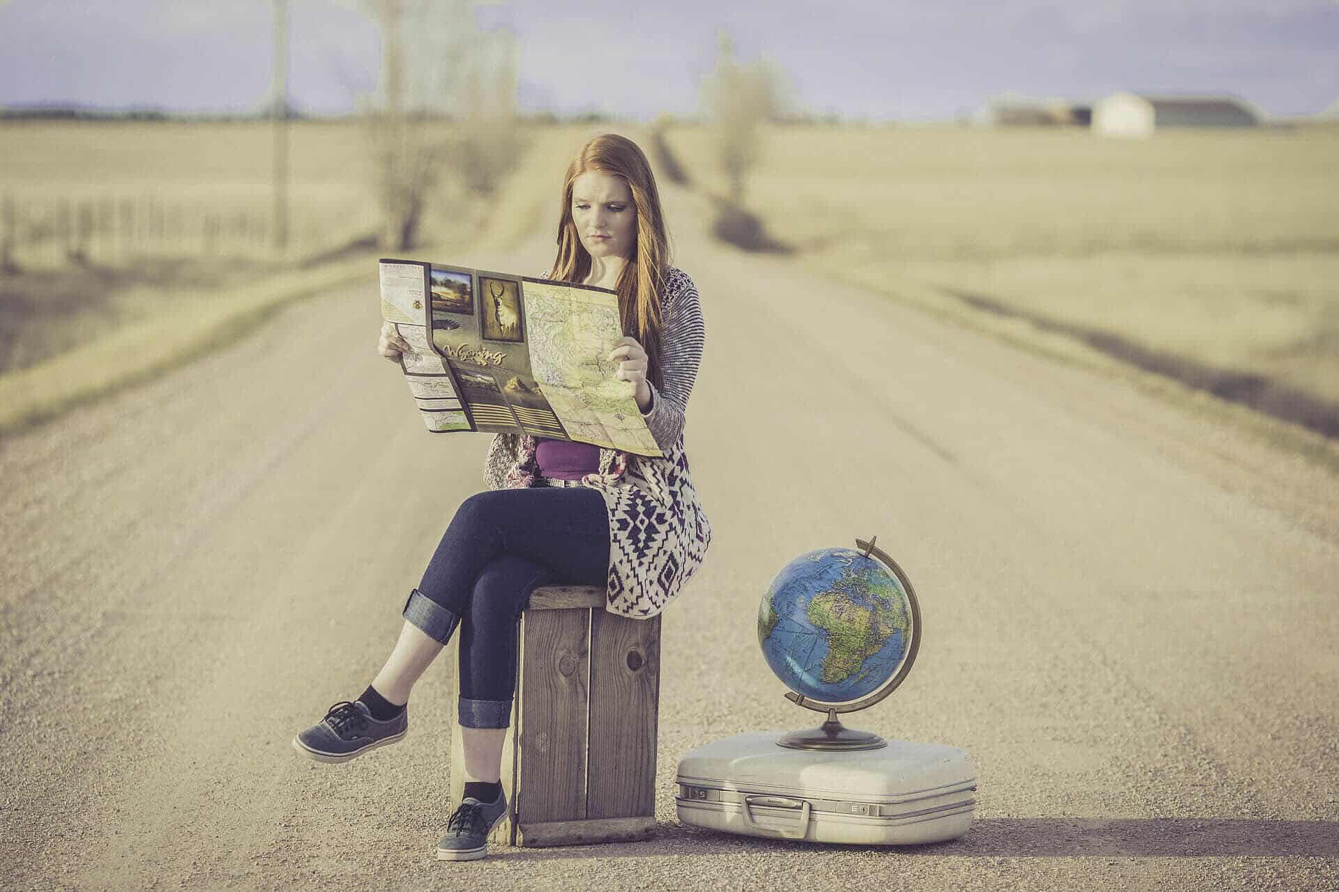Woman sitting near globe looking at map