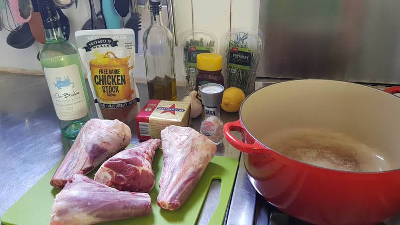 Ingredients for Lemon Lamb shanks laid out next to casserole pot