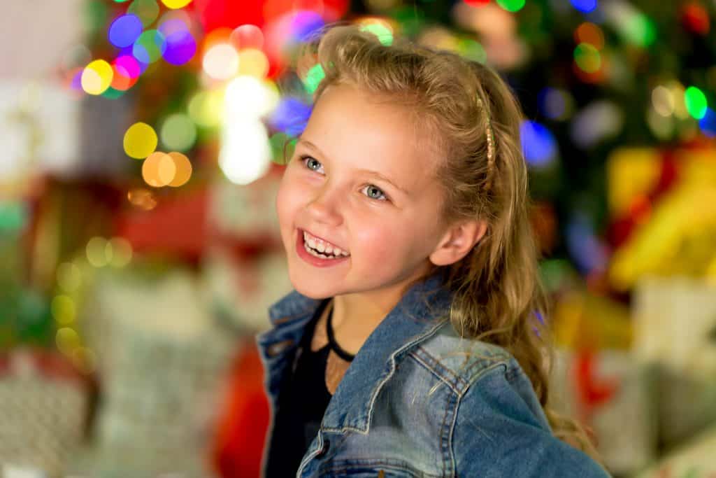 smiling little girl with Christmas lights in the background
