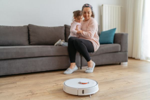 Mum And Baby Looking At Robot Vacuum Cleaning
