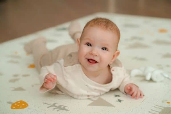 Happy child lying on baby play mat
