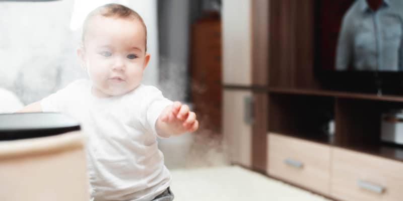 baby playing with the mist coming from an air humidifier