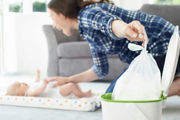 Mother using nappy bin after changing baby's diaper