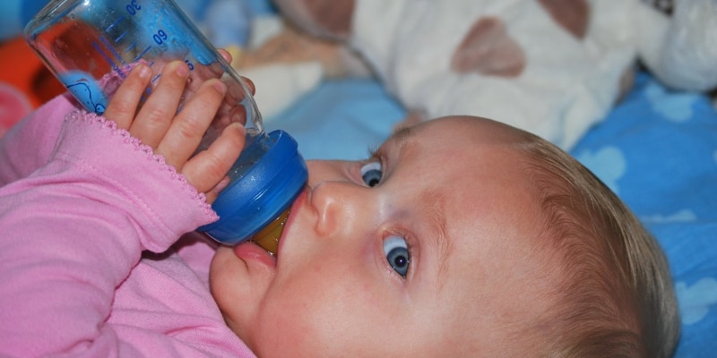 Baby drinking from a baby glass bottle