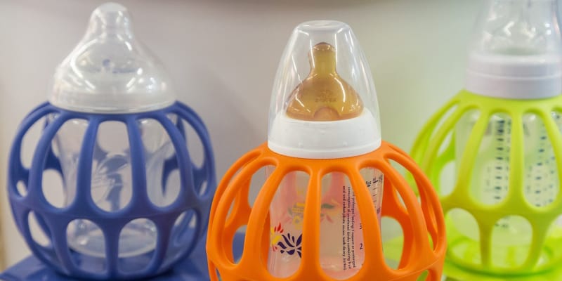 Different baby bottles in colourful baby bottle holders