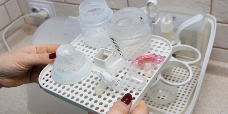 Mom using bottle steriliser to clean baby bottles