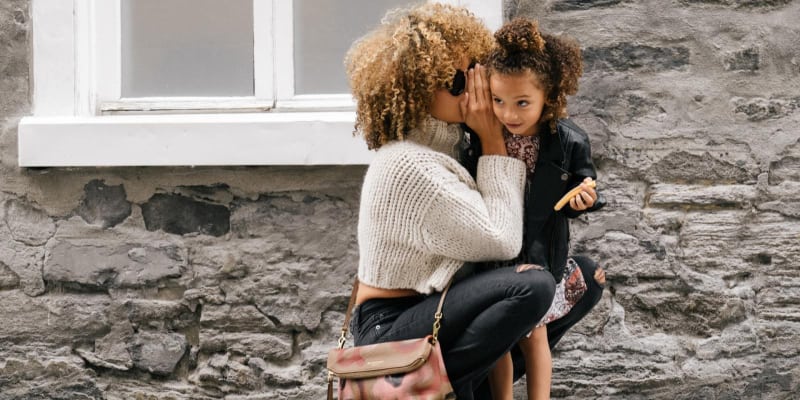 Mother whispering to her smiling daughter