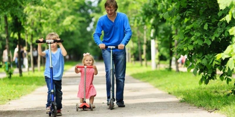 Kids learning to scoot with the help of dad