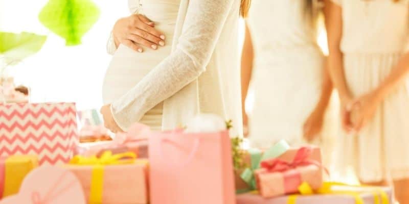 Pregnant woman surrounded with baby shower gifts