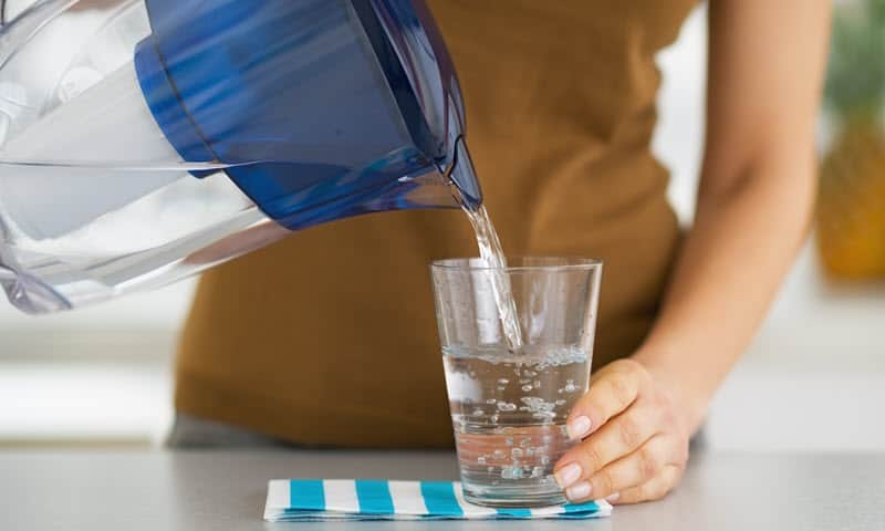 A woman using a Brita Blue jug water filter