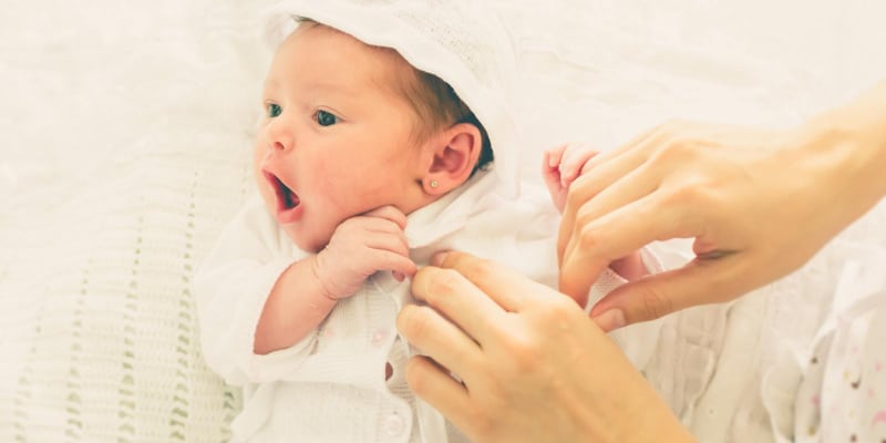 Adorable baby with funny face while getting changed