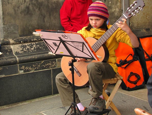 kid playing guitar and reading music