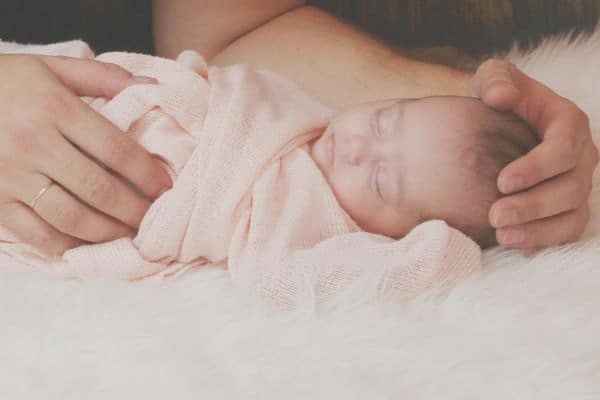 Parent holding newborn swaddled with pink cloth