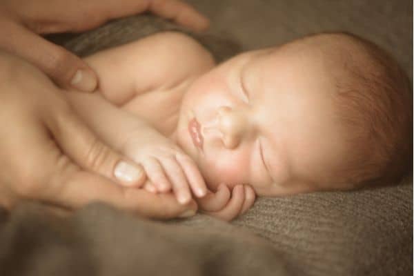 Parent holding baby to prepare for baby swaddling