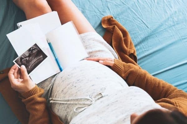 Expecting mum holding ultrasound photo pen and notebook