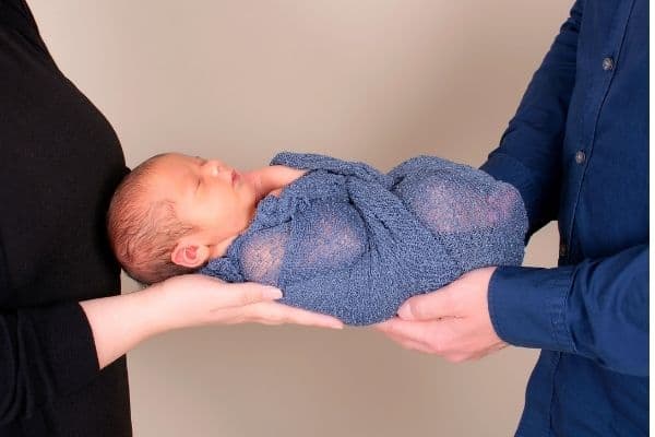 Parents holding child in baby swaddle