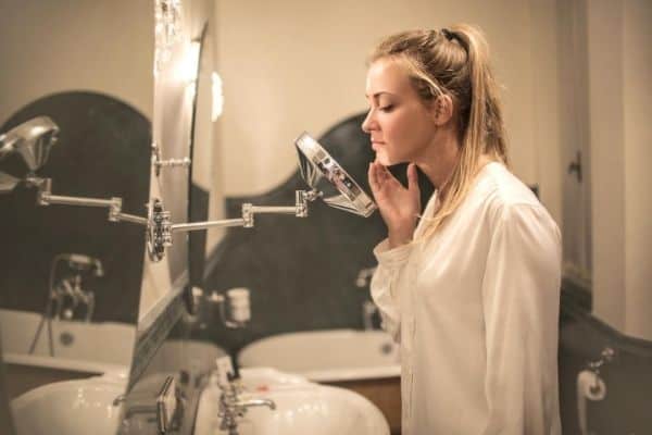 Woman inspecting face in front of the mirror