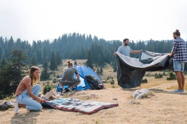 People setting up tent and mattress for camping