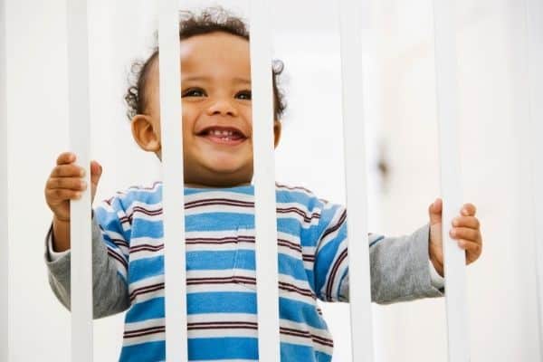 Laughing baby holding on baby gate