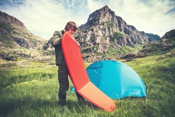 Man in the mountains holding a foldable sleeping mat