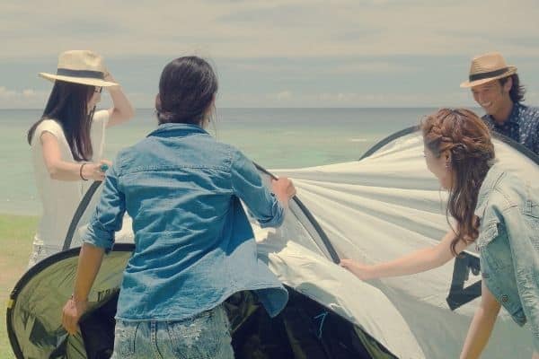 People folding up a beach tent
