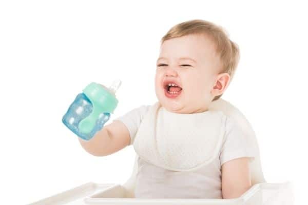Child making face while holding sippy cup