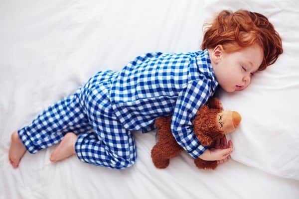 Toddler sleeping while hugging a plushy toy