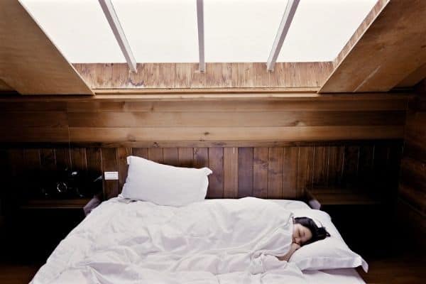 Woman sleeping in bed with white pillows and blanket