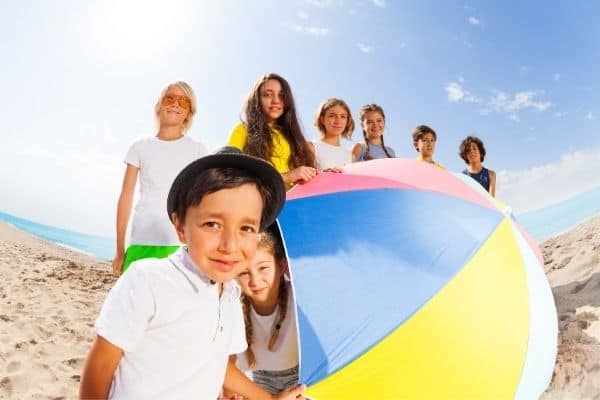 Kids at the beach holding a colourful beach umbrella