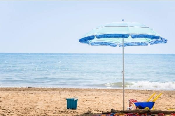 Blue beach umbrella and beach stuff for kids on the sand