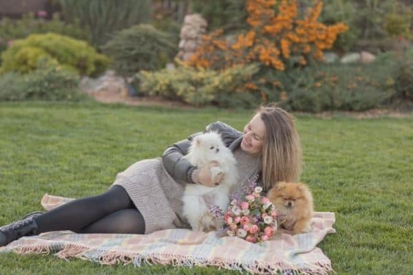 Woman outdoors hugging Pomeranian dogs