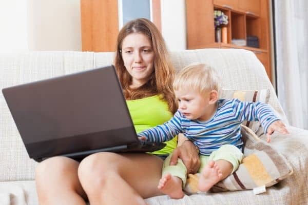 Mother using laptop while taking care of child