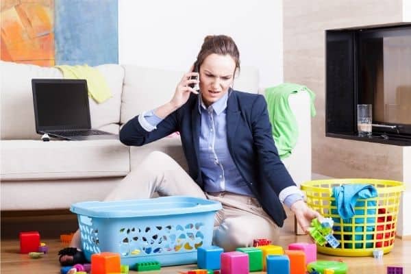 Mum talking on the phone while picking up toys in the living room