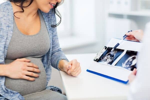 Pregnant woman and sonographer looking at baby's ultrasound images
