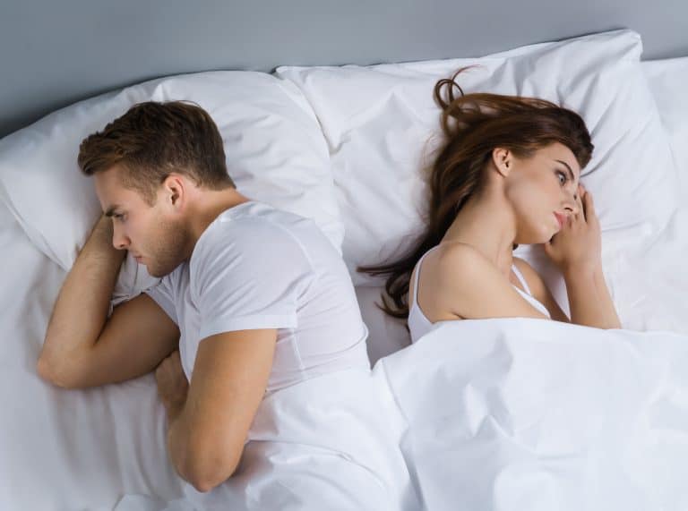 Unhappy young couple in bedroom