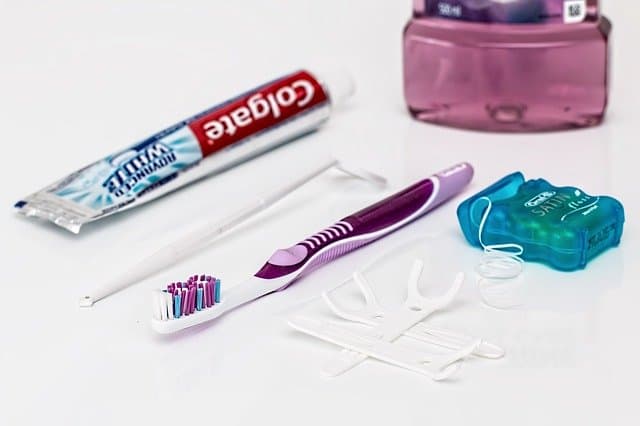 Toothbrush, toothpaste and dental floss sitting on white surface
