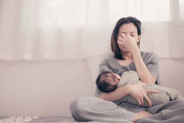 mother showing exhaustion while holding newborn baby