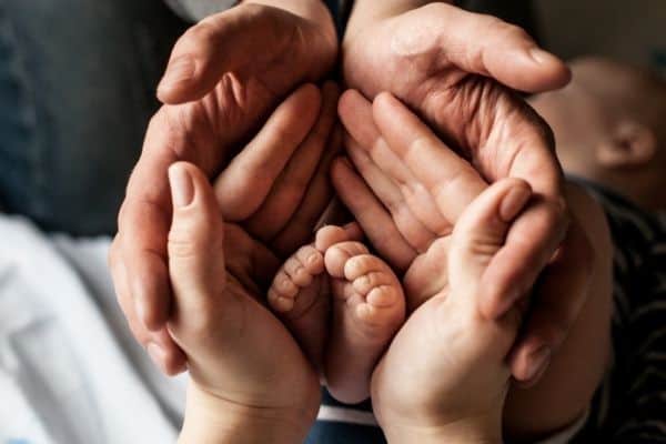 baby's feet between parent's hands