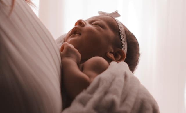 cute newborn baby sleeping on mums arms