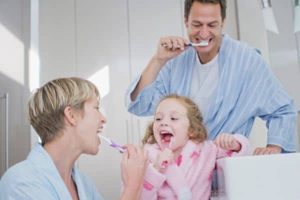 family of three brushing teeth