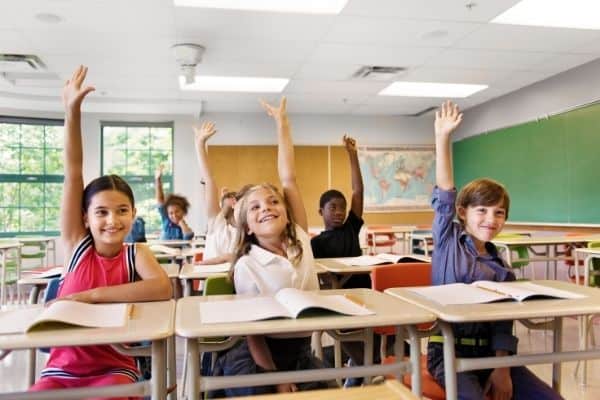 kids in classroom raising hands