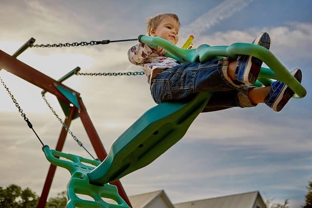 young boy on playground swing