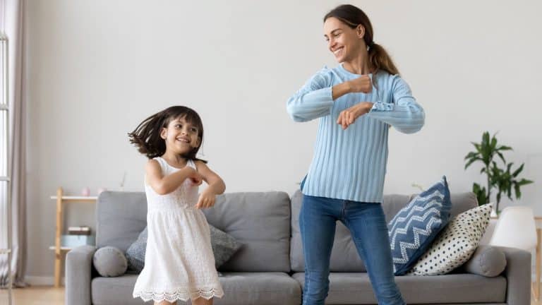 A little girl and her nanny dancing in a lounge room