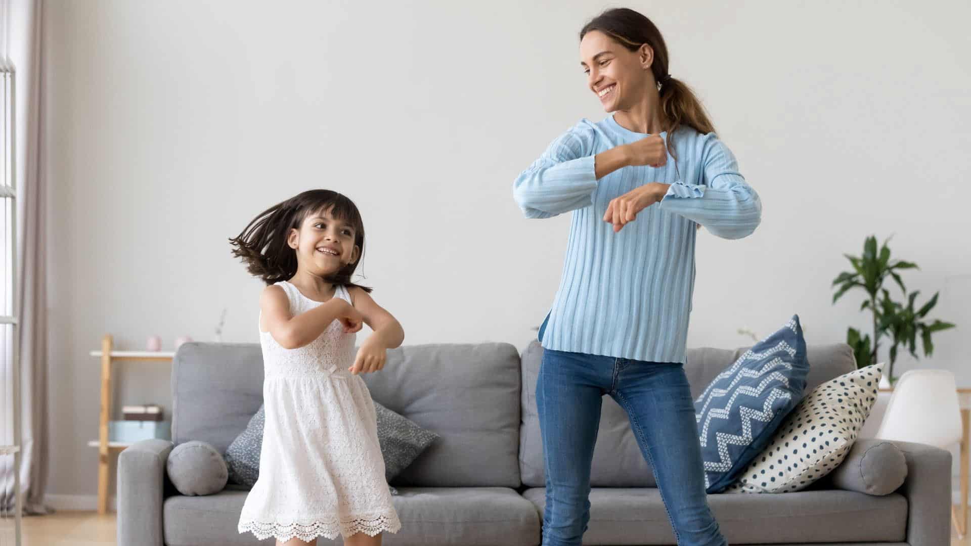 A little girl and her nanny dancing in a lounge room