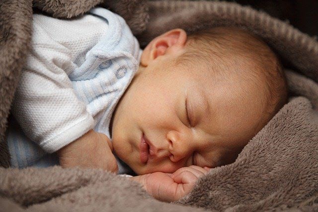 Baby sleeping on side with tiny hands in view