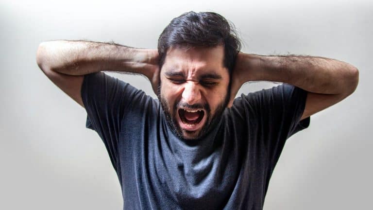 Man holding hands over ears with pained expression on face