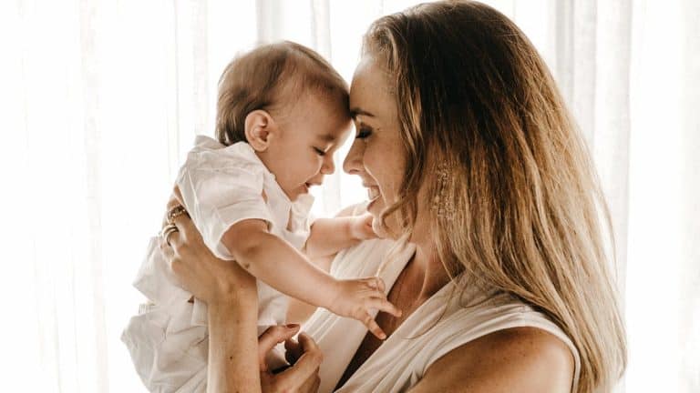 Mother holding baby head to head and smiling