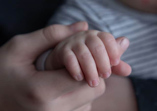 Mothers hand holding tiny hand of a baby