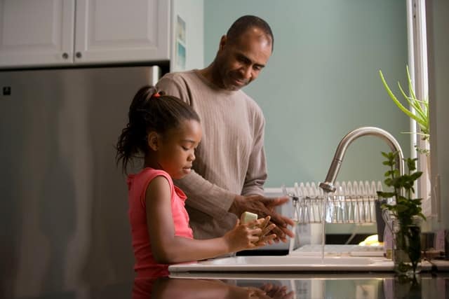 dad teaching child how to wash dishes
